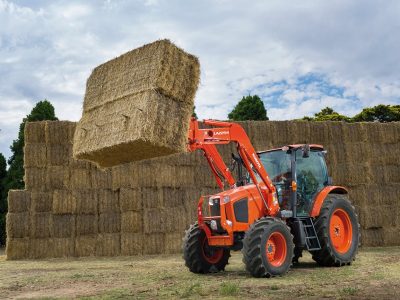 M Series Kubota Tractor with loader lifting bale